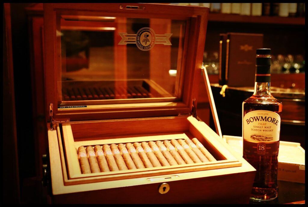 Humidor para puros de madera con interior de cedro y varios habanos sobre una superficie oscura