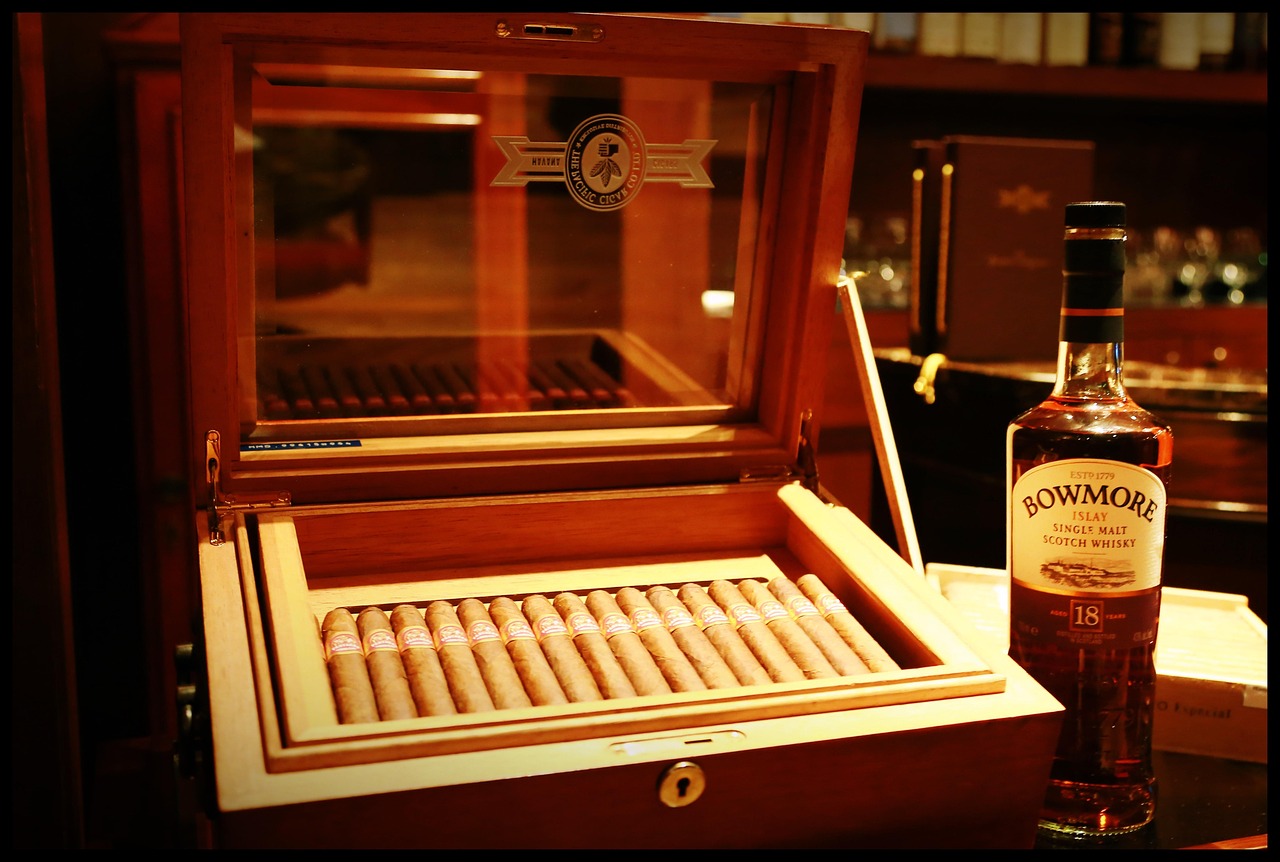 Humidor para puros de madera con interior de cedro y varios habanos sobre una superficie oscura